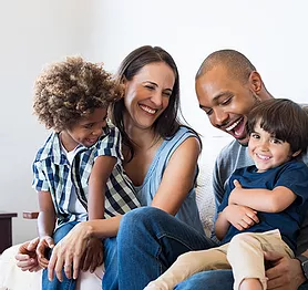 happy family sitting together on a couch, laughing and smiling